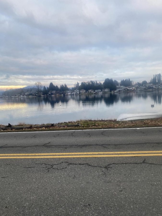 The road with cracks that you can see that were once there. The lake reflecting the other side of the lake. With it being a blue sky but freezing cold. Running at a steady pace but can’t stop to even take a minute to look at the beauty before them. December 5th, 2022 3:48 PM.
