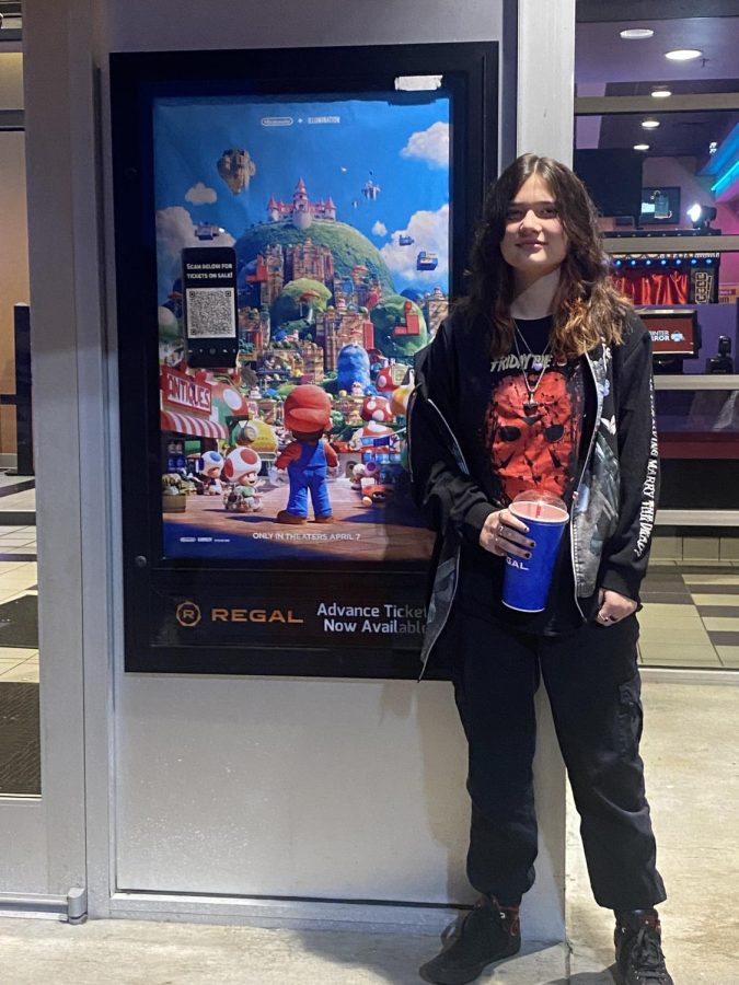 Student journalist Chloe Reynolds poses in front of the Mario Bros. poster.